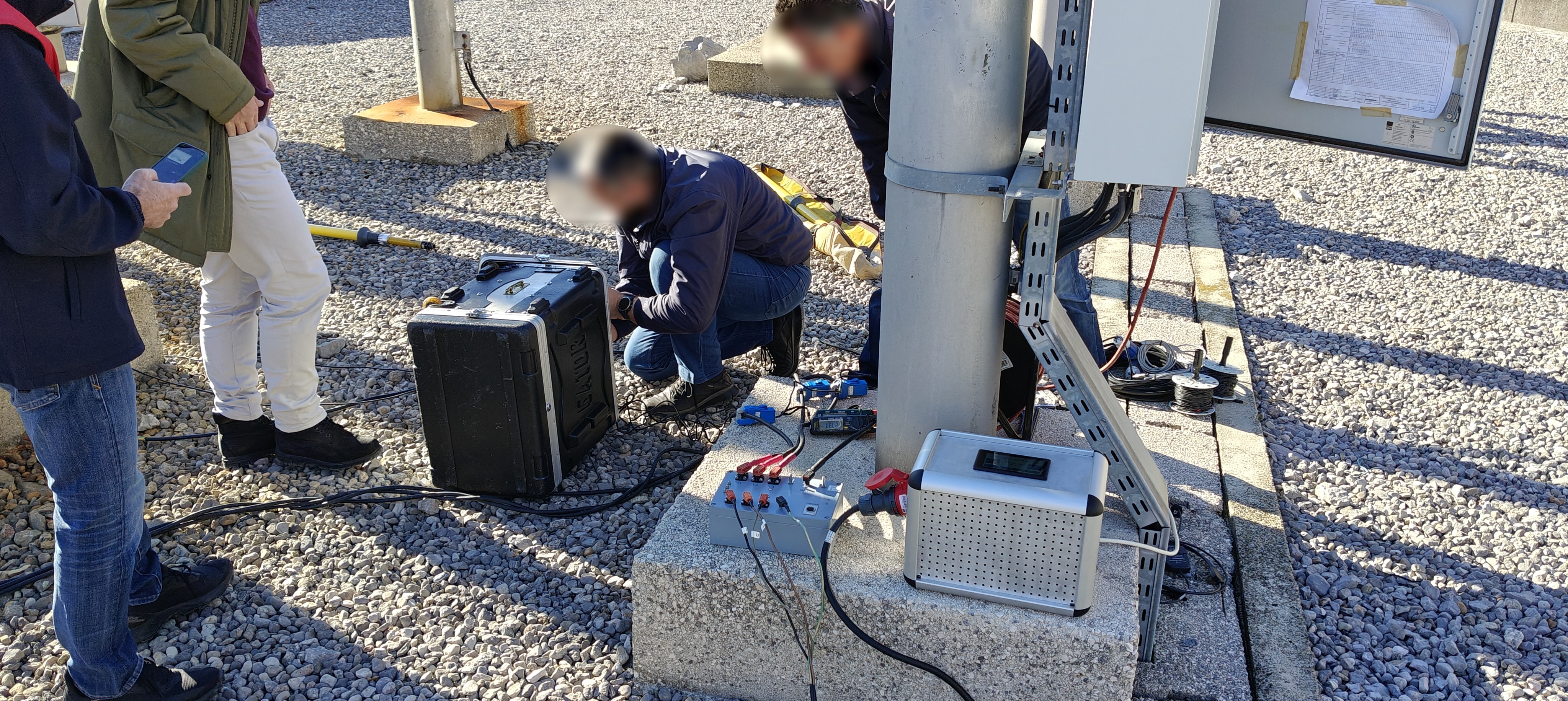 Field team validating the AC current source beside utility equipment.